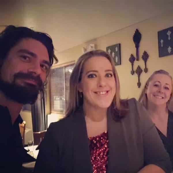 Three smiling customers, two women and one man, enjoying their time at Bete-Lukas Ethiopian restaurant.
