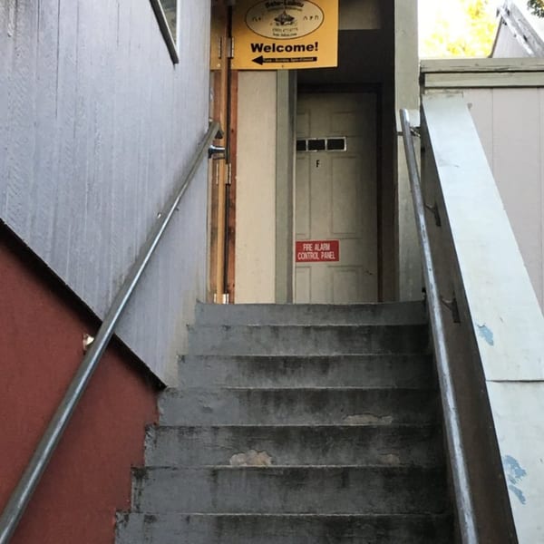 Exterior view of Bete-Lukas Ethiopian restaurant entrance, up a concrete staircase with a "Welcome!" sign.