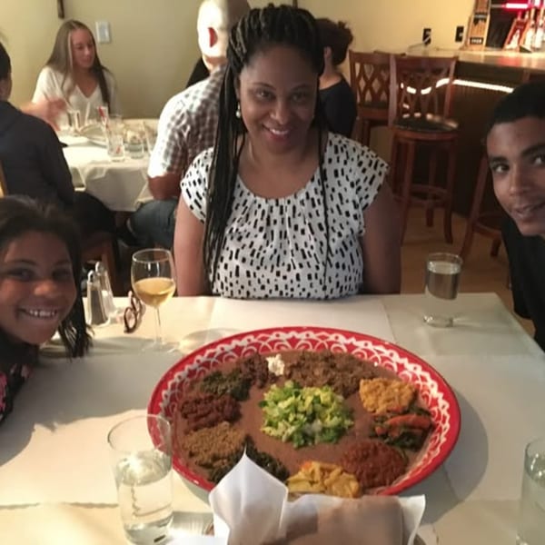 Family enjoying a large platter of Ethiopian food at Bete-Lukas restaurant.