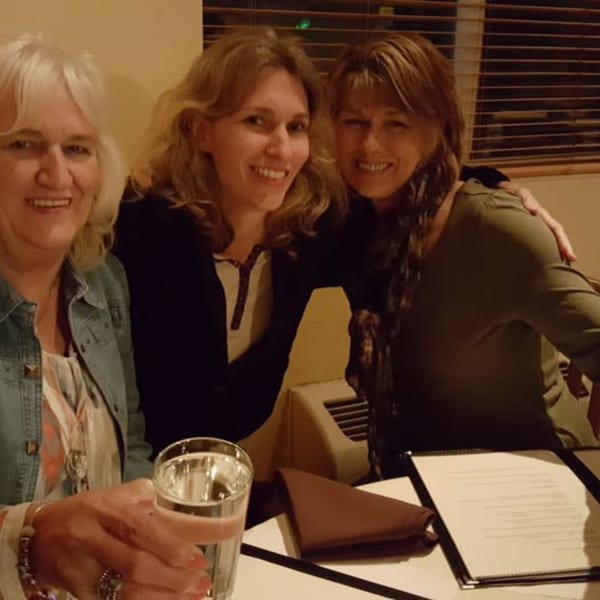 Three smiling women enjoying a meal together at Bete-Lukas Ethiopian Restaurant.