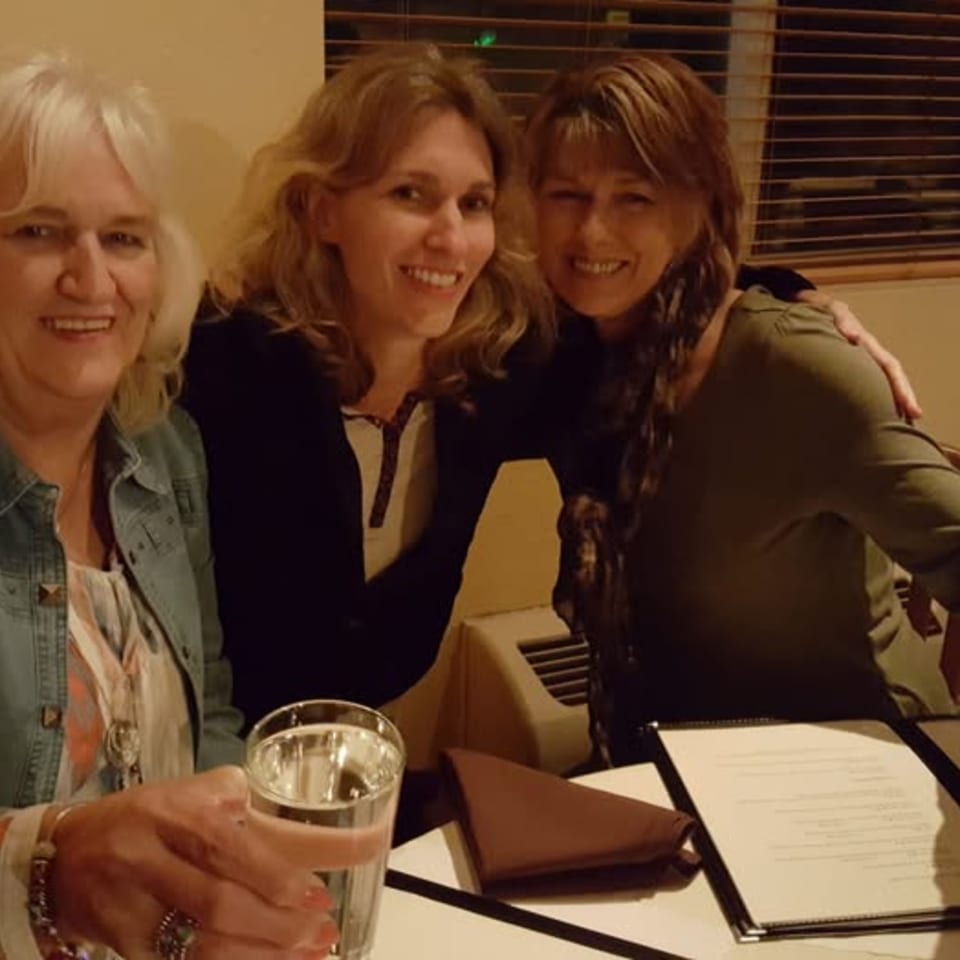 Three smiling women enjoying a meal together at Bete-Lukas Ethiopian Restaurant.