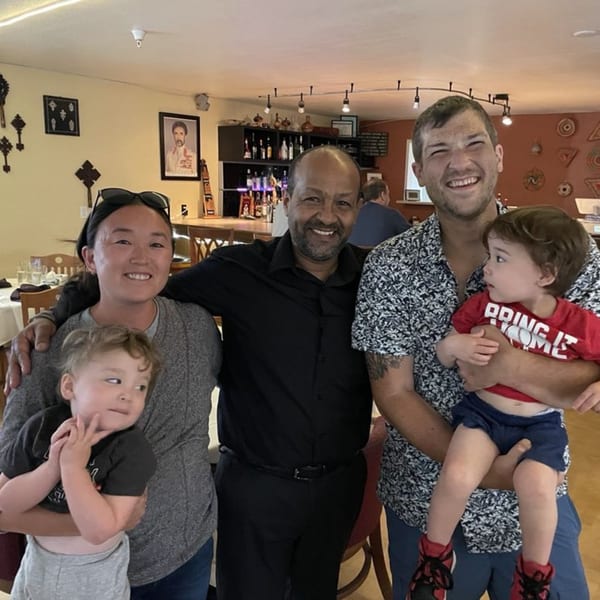 A family with two young children poses with a smiling man in an Ethiopian restaurant.