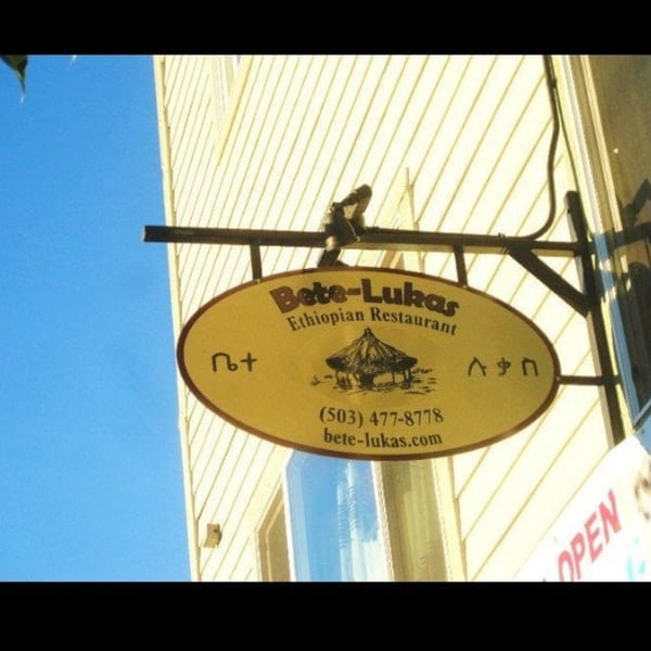 Oval Bete-Lukas Ethiopian Restaurant sign with a hut illustration, phone number, and website.