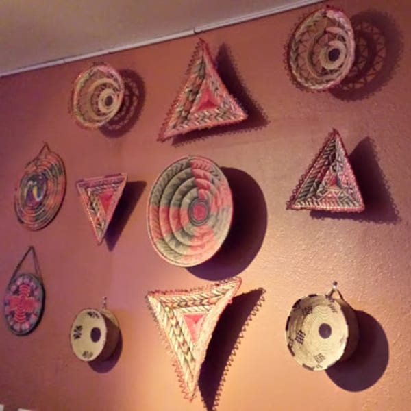 A wall adorned with various Ethiopian woven baskets and decorative plates in warm colors.